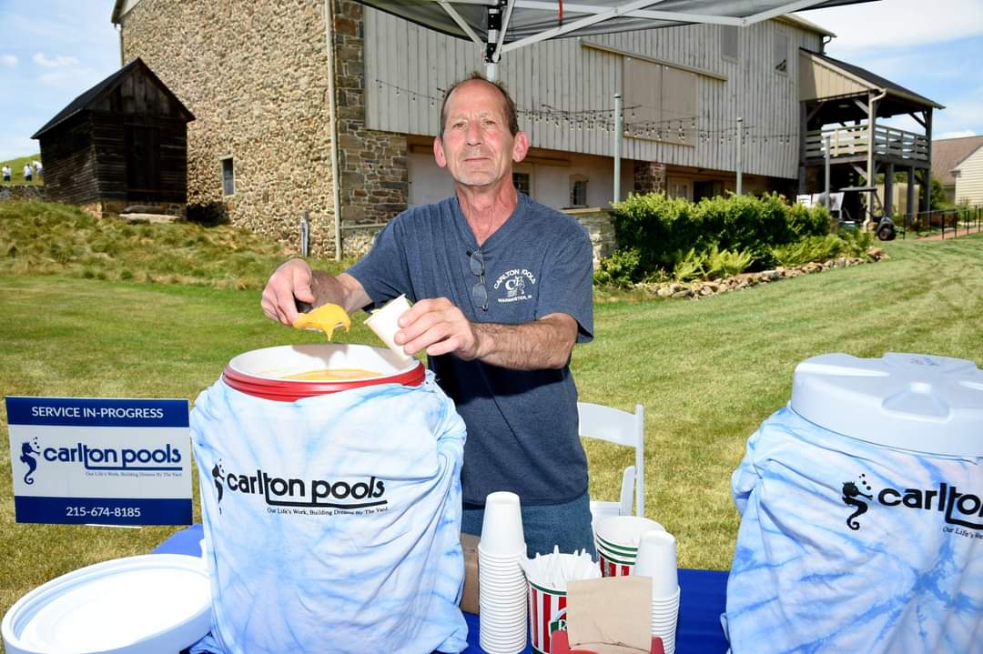 carlton pools team member serving water ice at the barkann foundation's fall golf classic